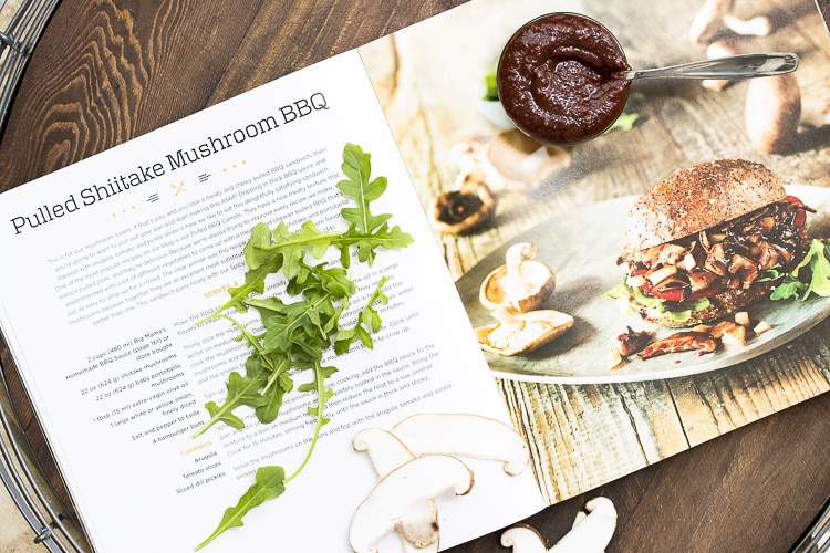 Vegan pulled pork sandwich recipe page with arugula pieces and dish of BBQ sauce on top