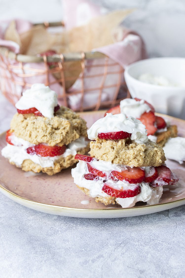 Pink plate with two shortcake biscuits filled with whipped cream and fresh strawberries