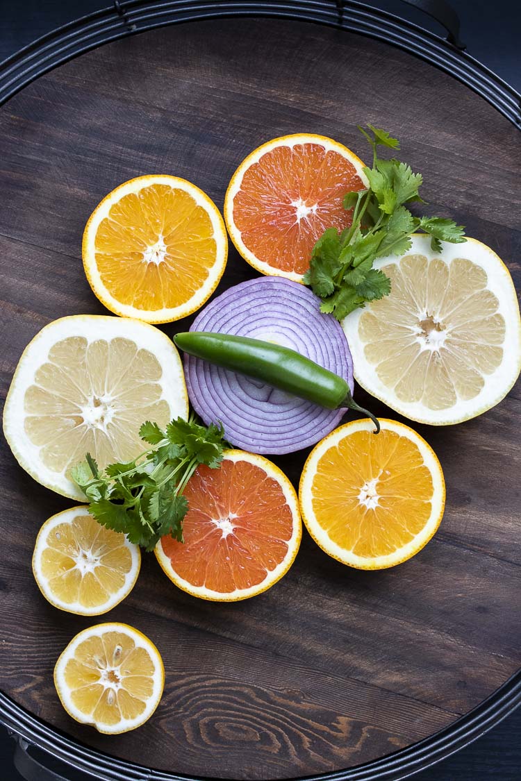 Top view of grapefruit and orange halves with red onion, cilantro and a Serrano pepper