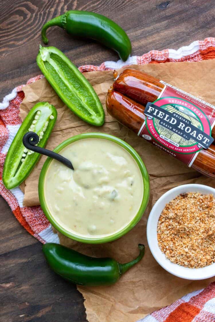 Top view of vegan sausages, jalapeños and bowl of vegan white cheese sauce