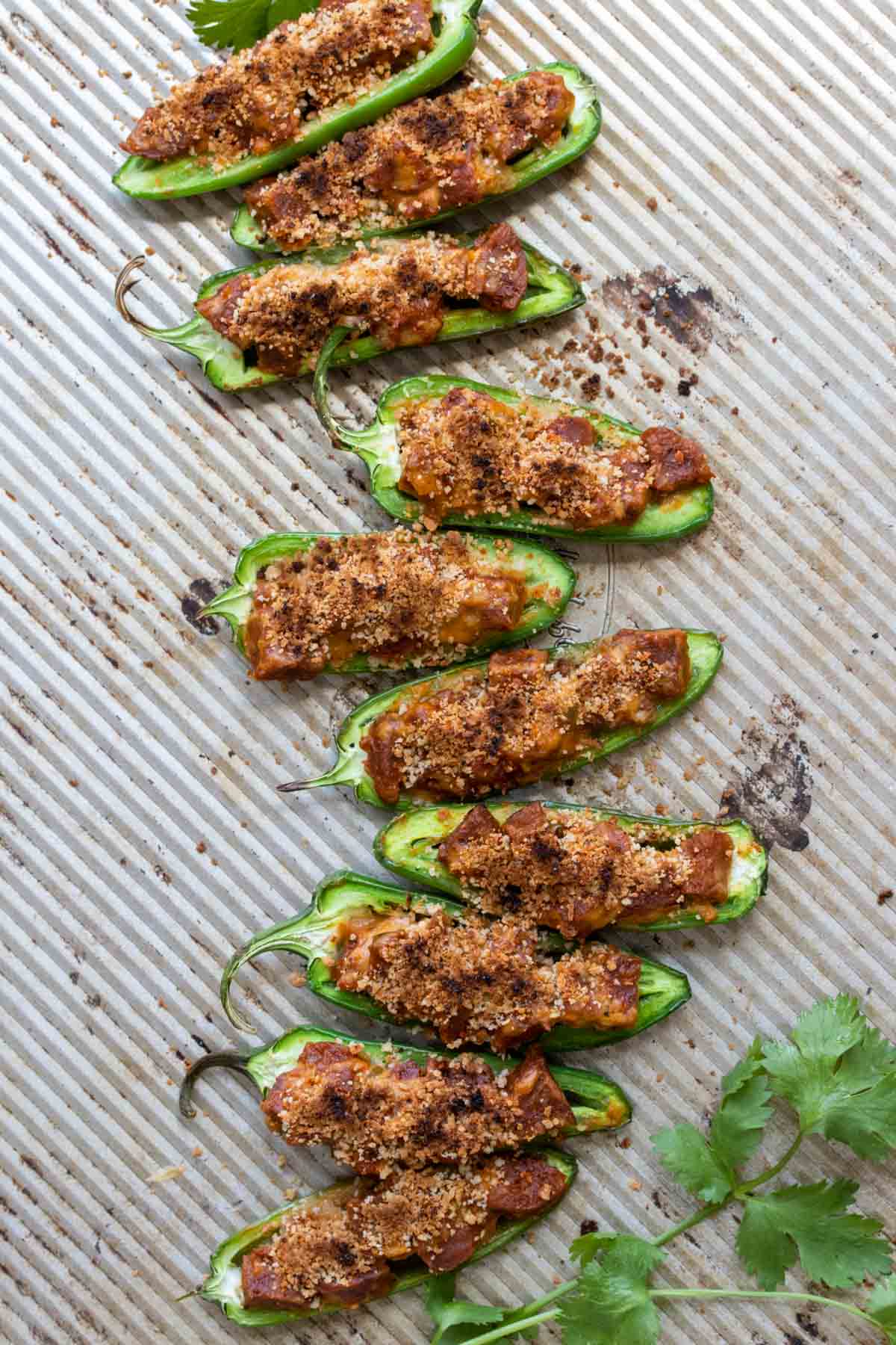 Top view of vegan sausage stuffed jalapeños on a baking sheet