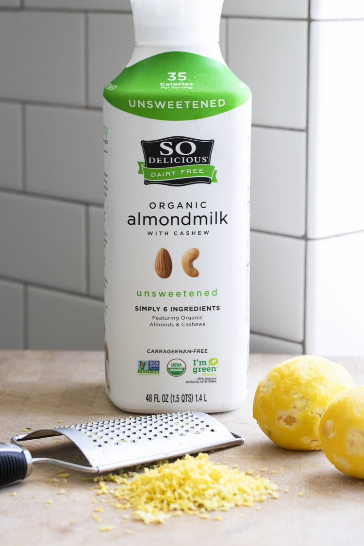 Bottle of So Delicious almondmilk with cashew next to grated lemon zest