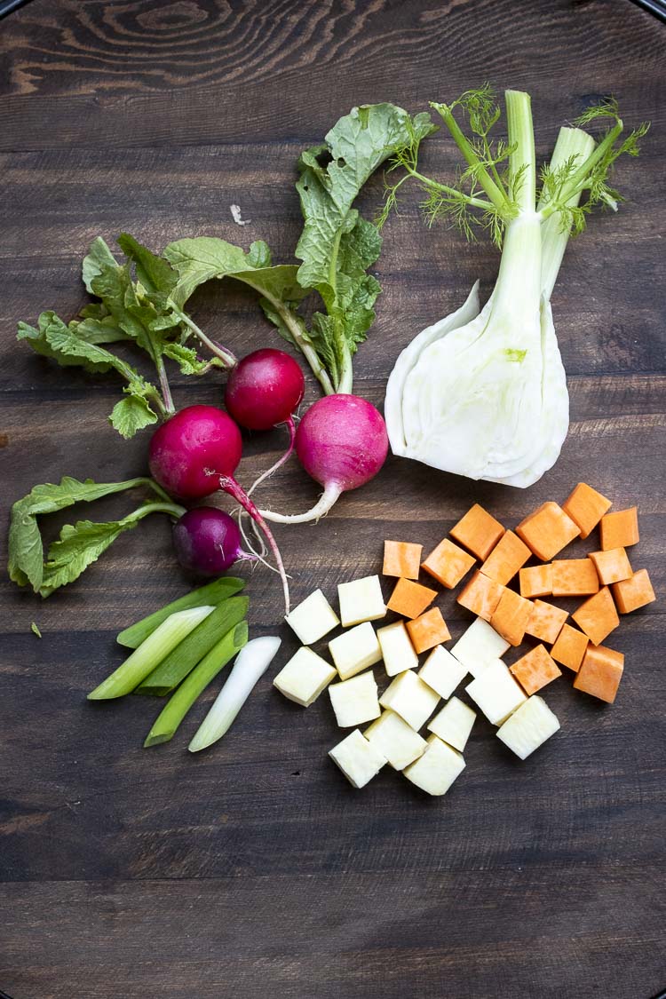 Top view of radishes and cut fennel, sweet potato and green onions