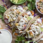 Top view of roasted veggie tacos surrounded by bowls of toppings