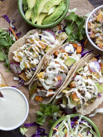 Top view of roasted veggie tacos surrounded by bowls of toppings