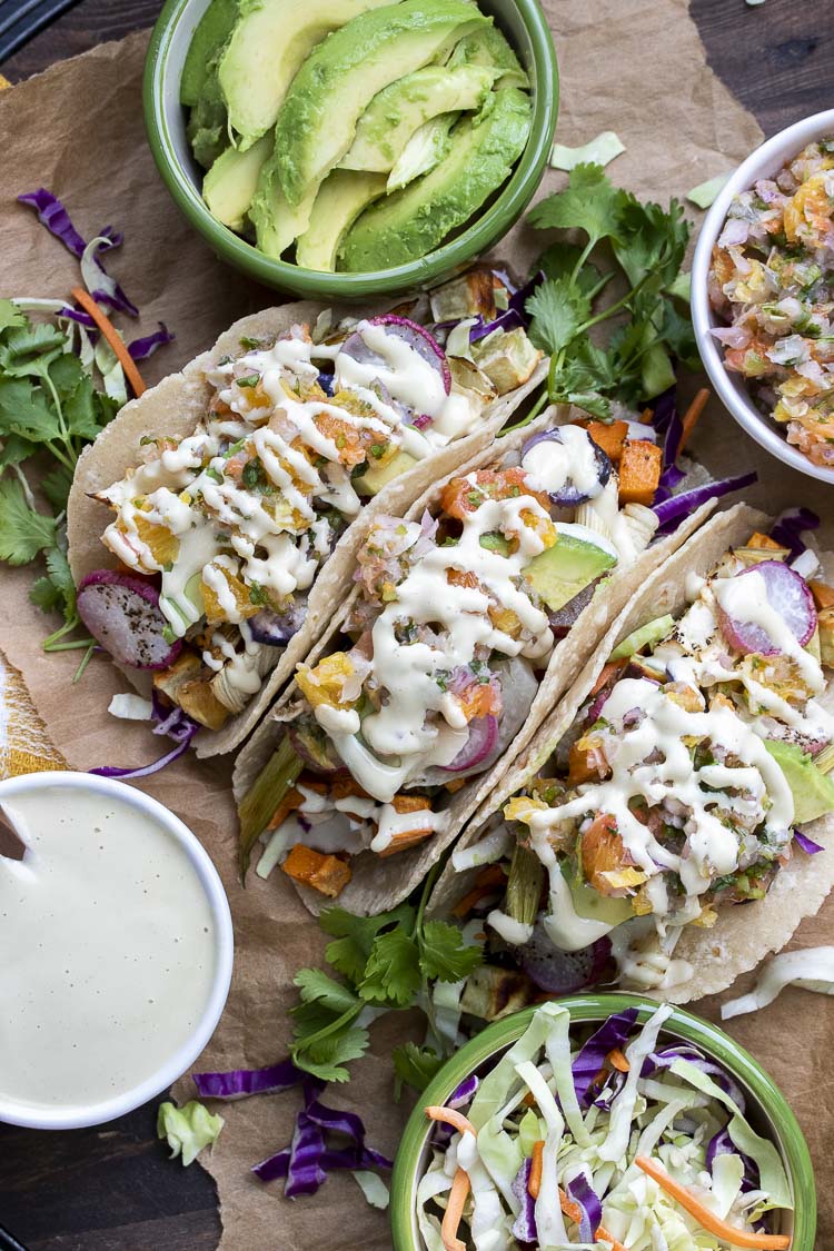 Top view of roasted veggie tacos surrounded by bowls of toppings 