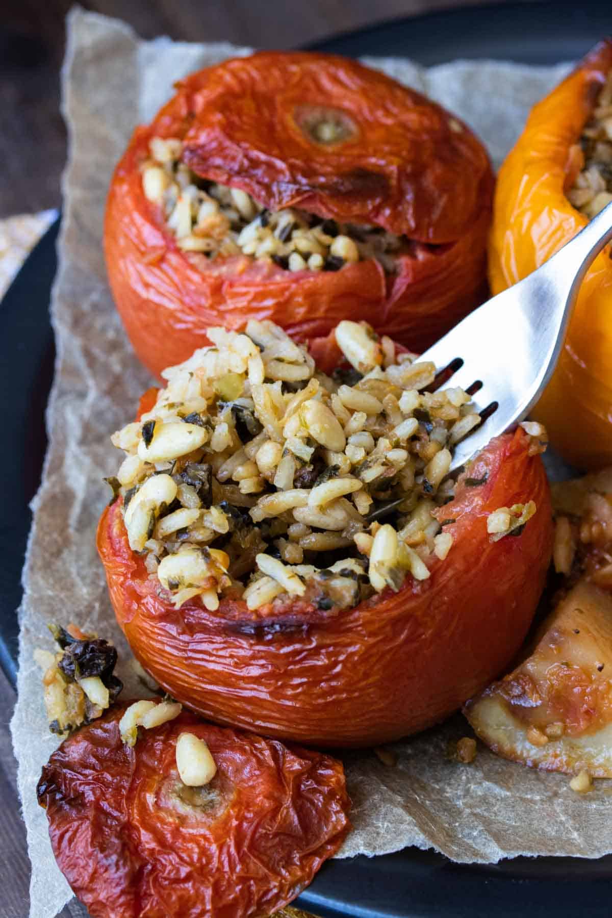 Fork scooping rice from a baked stuffed tomato 