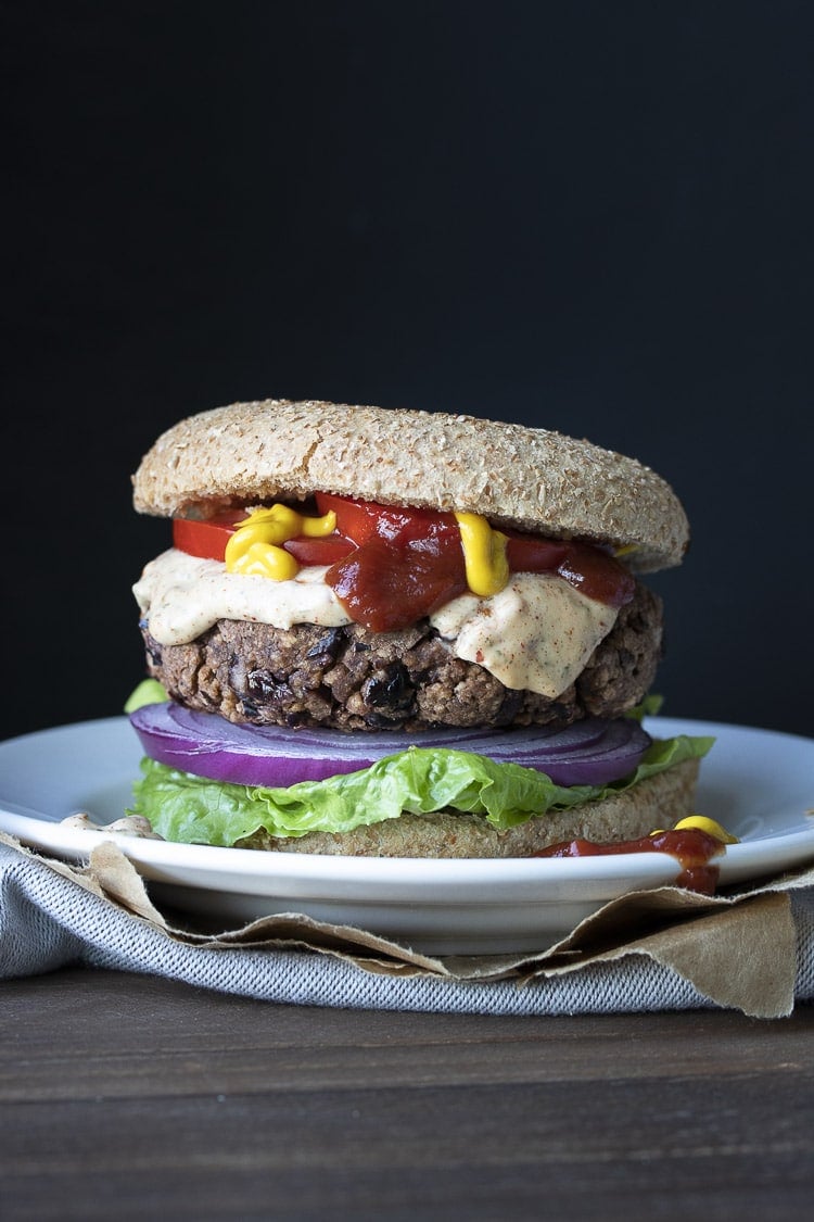 Black bean burger topped with ketchup, mustard, pink sauce, red onions and lettuce