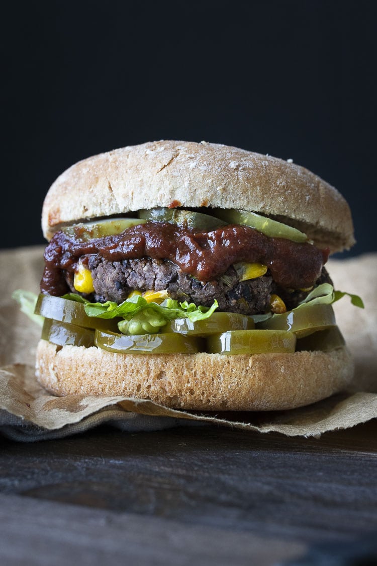 Black bean and corn burger on a bun with pickles, BBQ sauce, lettuce and jalapeños