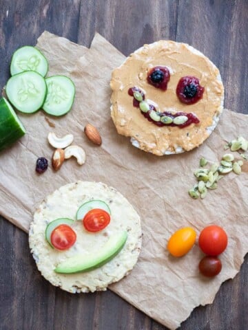 Rice cakes decorated as faces using nut butter, hummus, seeds, veggies, dried fruit and nuts.