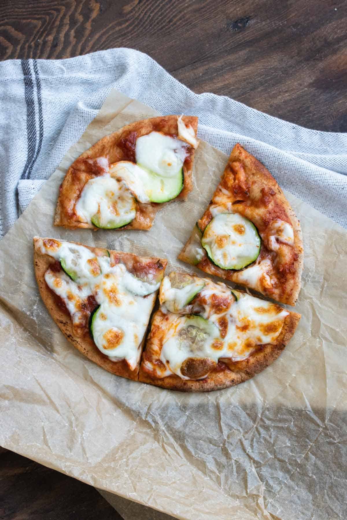 Pita bread topped with pizza sauce, zucchini slices and cheese and toasted as a pizza