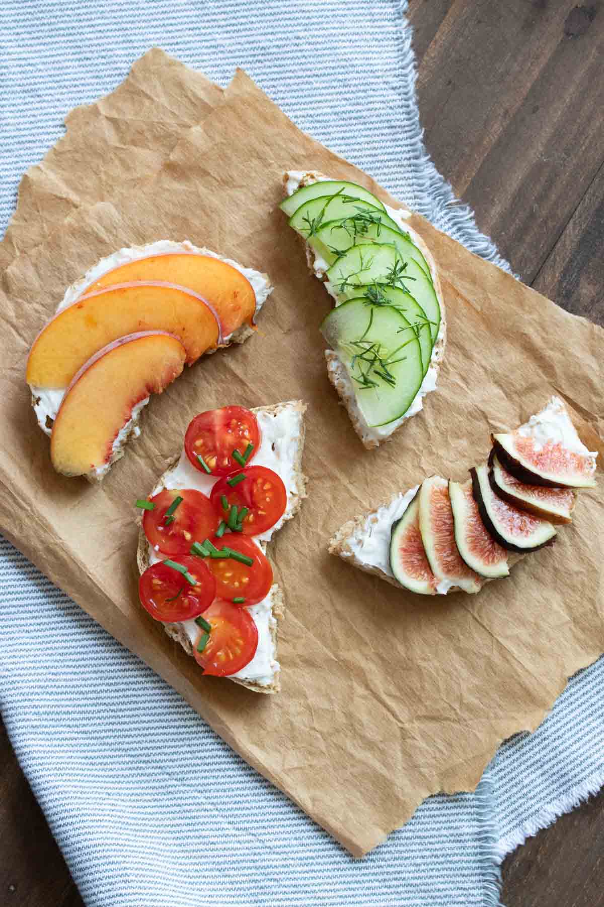 Quarters of a bagel topped with cream cheese and fruit and veggies