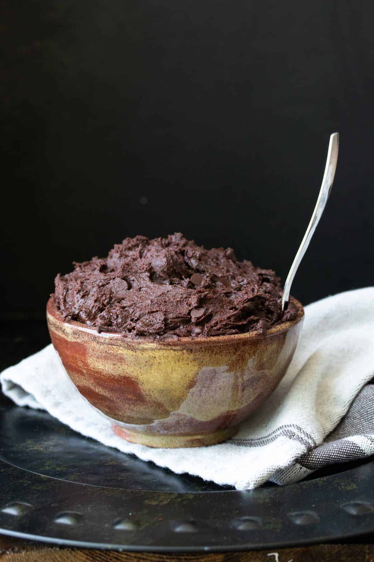 Spoon in a brown and yellow marbled bowl filled with brownie batter.