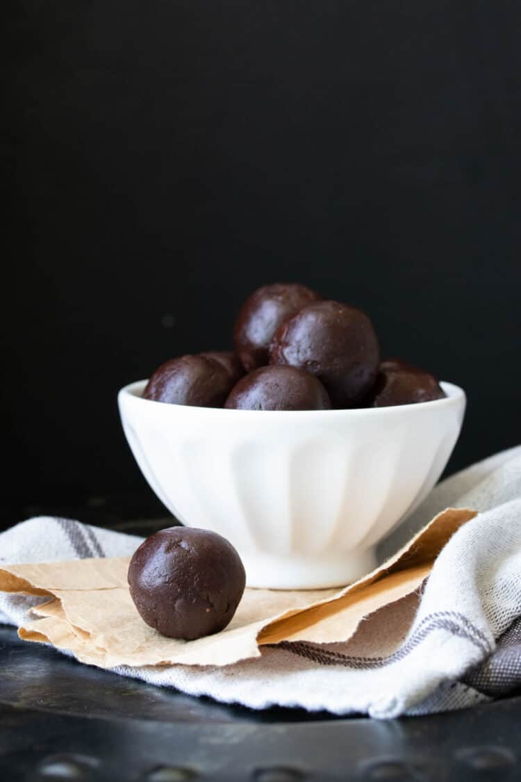 White bowl filled with raw brownie batter balls on a light grey towel.