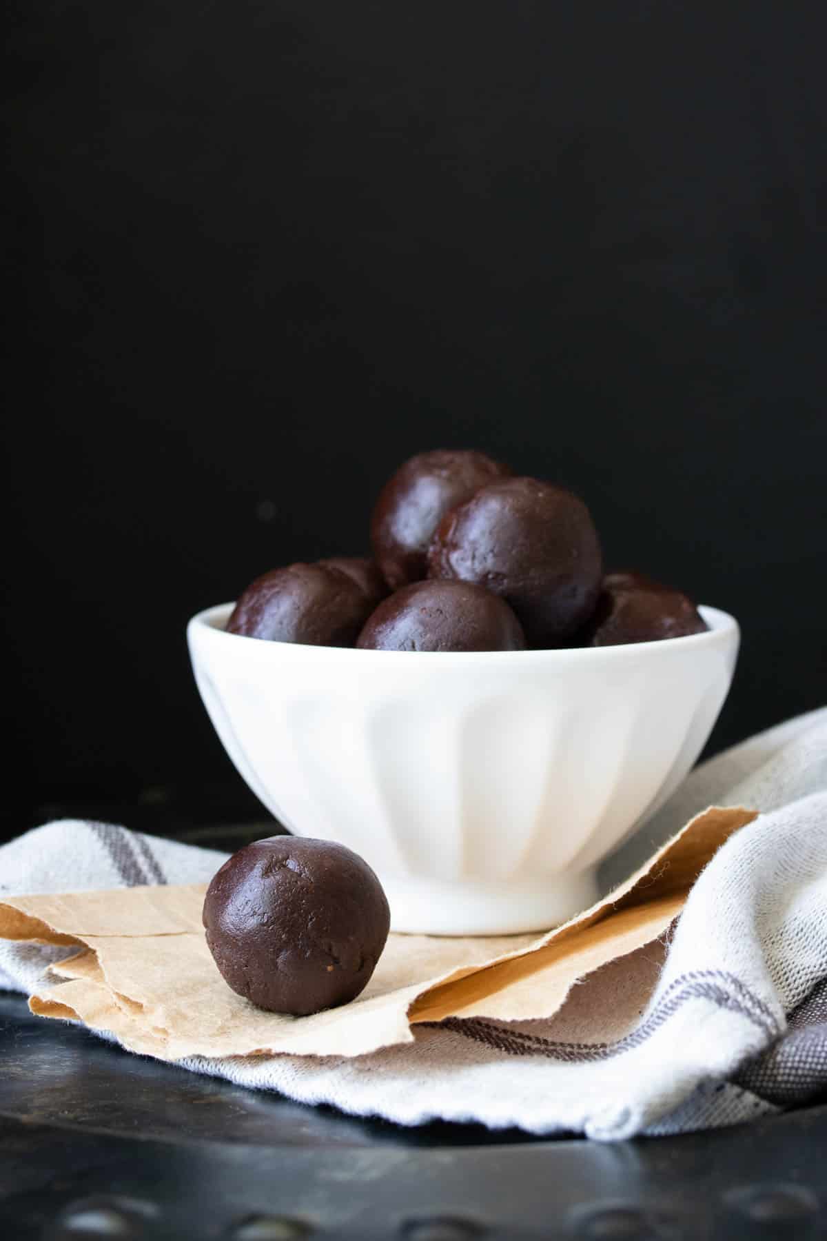 White bowl filled with raw brownie batter balls on a light grey towel