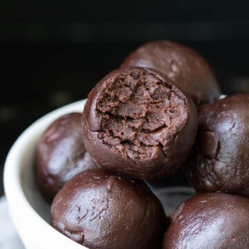 Pile of raw brownie batter balls, one with a bite out of it