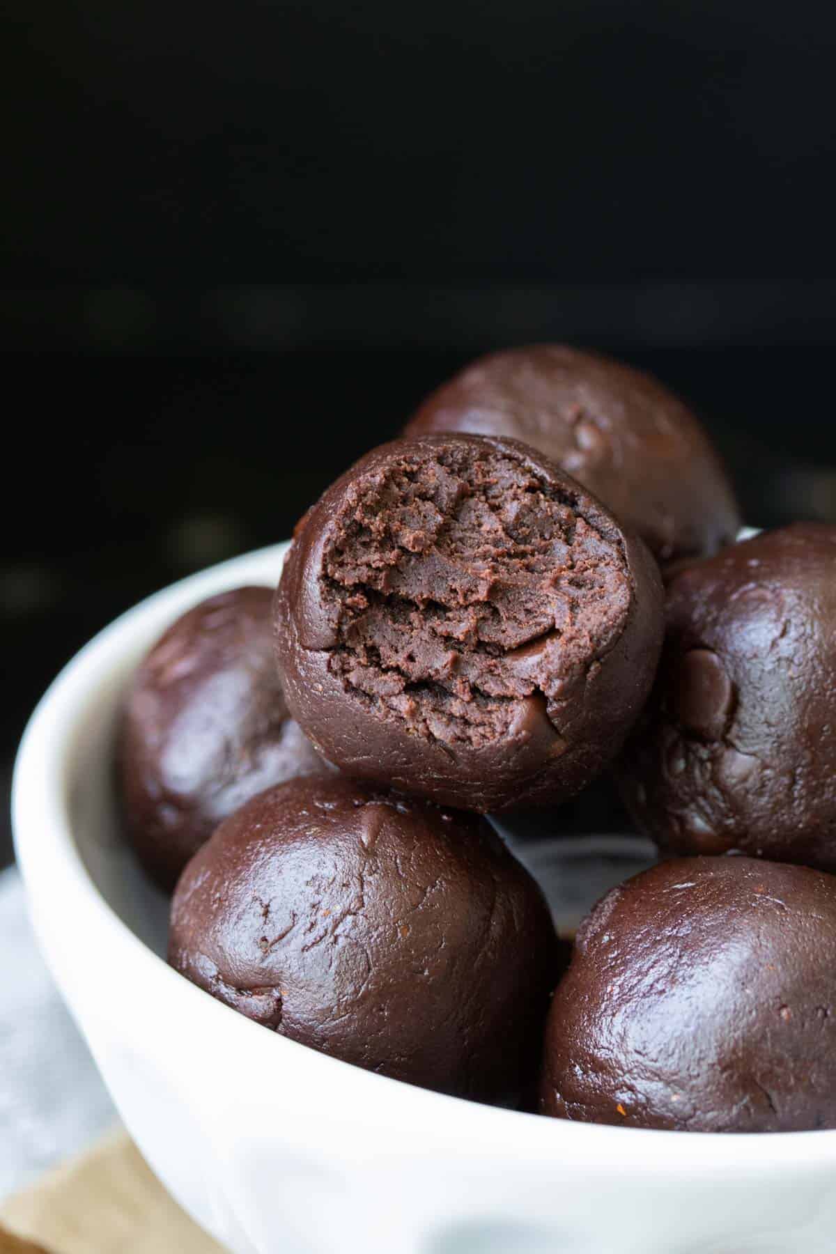 Pile of raw brownie batter balls, one with a bite out of it.