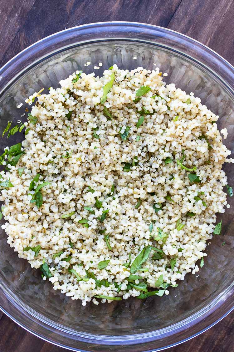 White quinoa mixed with cilantro in a glass bowl