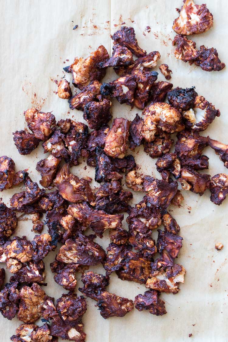 Baked BBQ cauliflower bites spread out on tan parchment paper