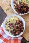 Top view of two white bowls with quinoa, cabbage slaw and BBQ cauliflower bites