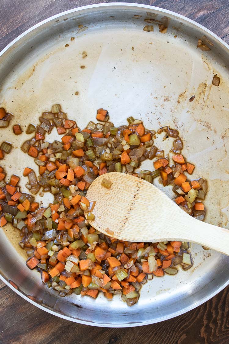 Celery, carrots and onion cooking in a small amount of liquid in a metal pan