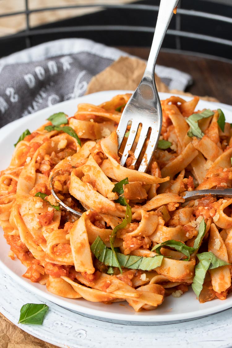 Fork twisting noodles mixed with meaty red sauce on a spoon