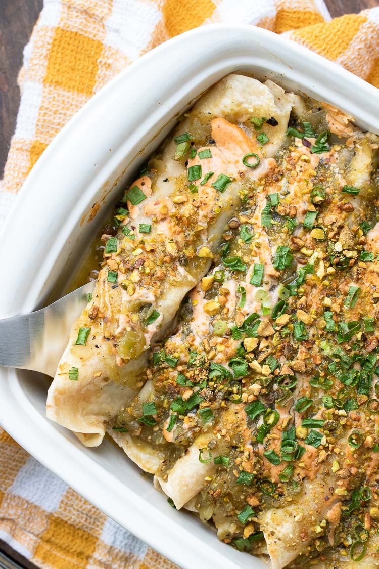 Top view of enchiladas topped with green and pink sauces and green onions