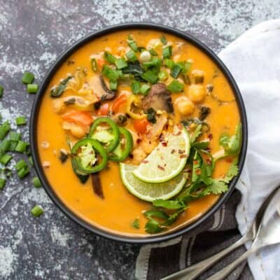 Vista geral da sopa de caril de coco de laranja com vegetais numa tigela preta