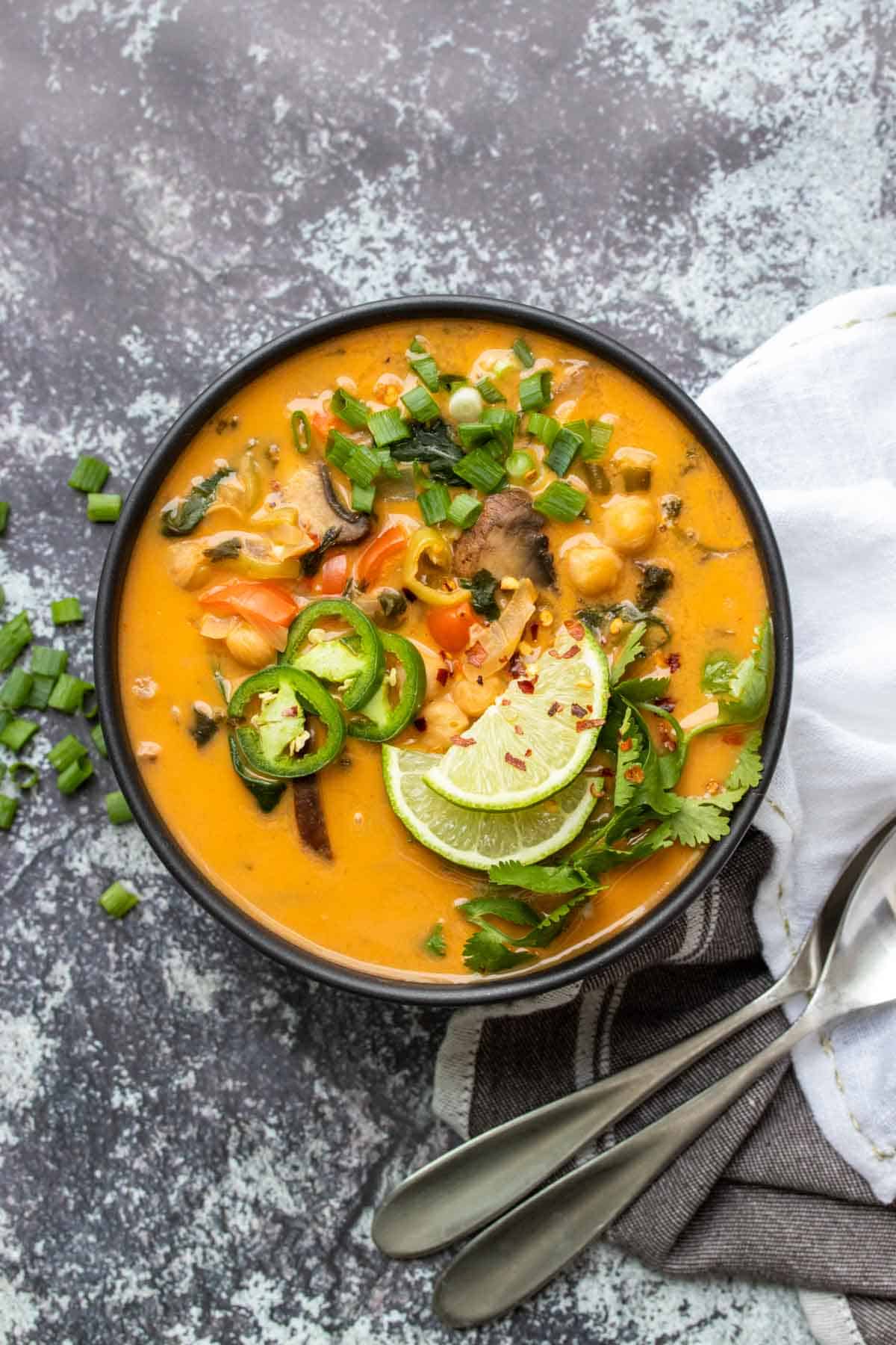 Vista superior de la sopa de coco y curry con verduras en un bol negro