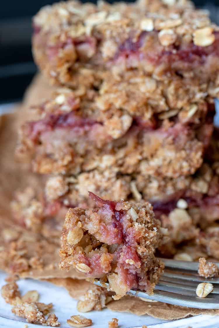 Fork with a bite of cranberry crumble bar resting on a white plate