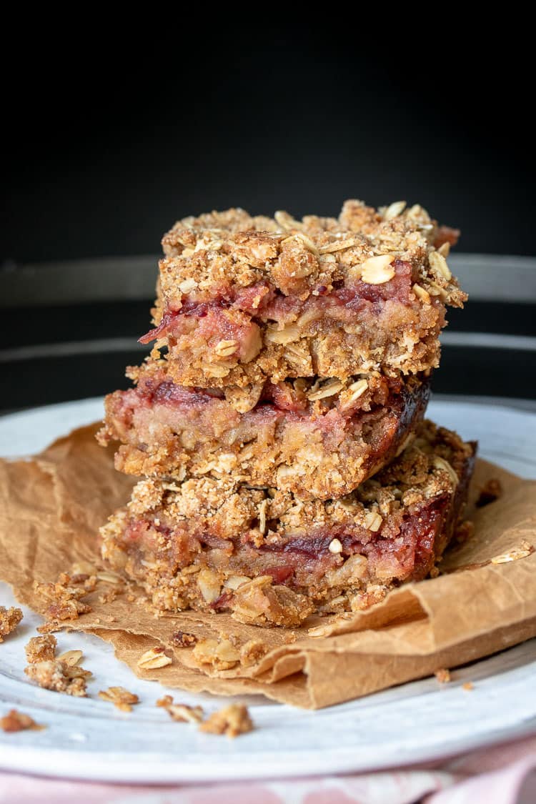 A stack of three cranberry crumble oatmeal bars on a white plate