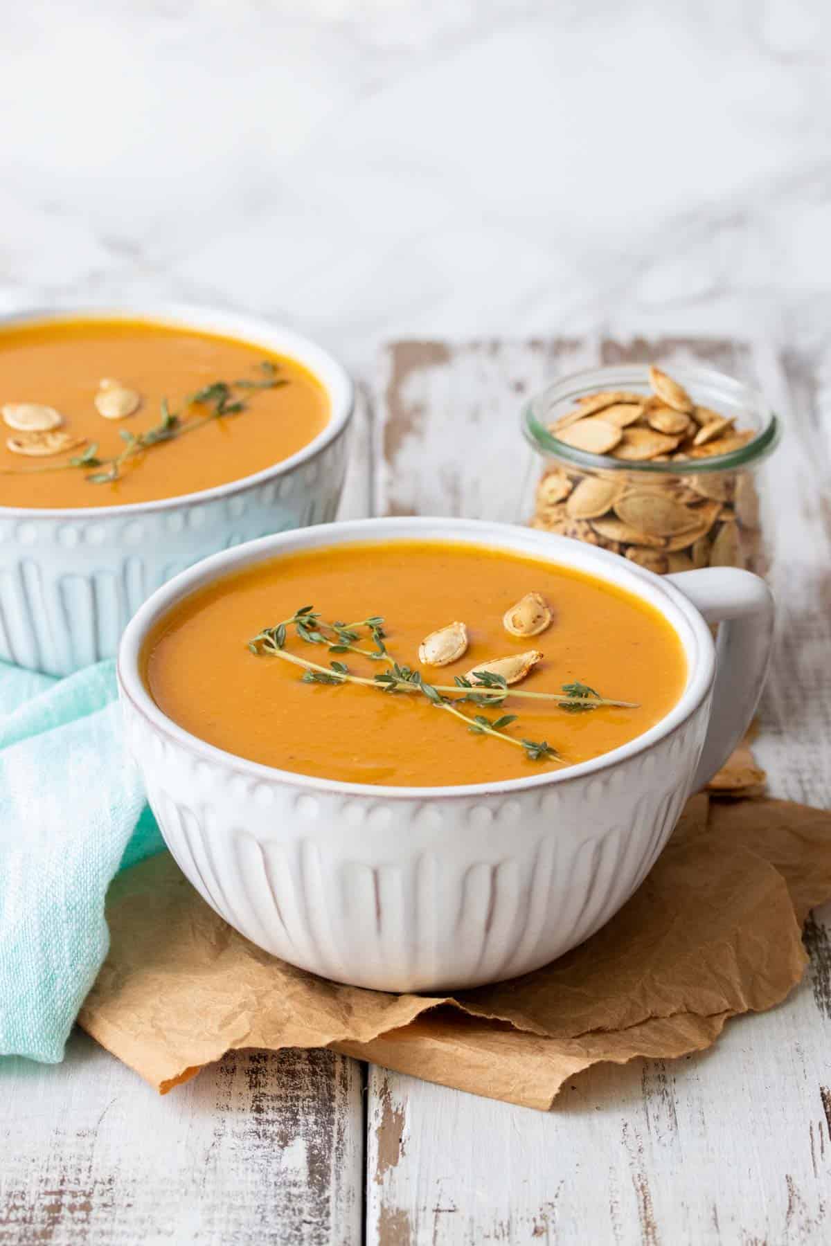 Front view of butternut squash soup in two white soup mugs