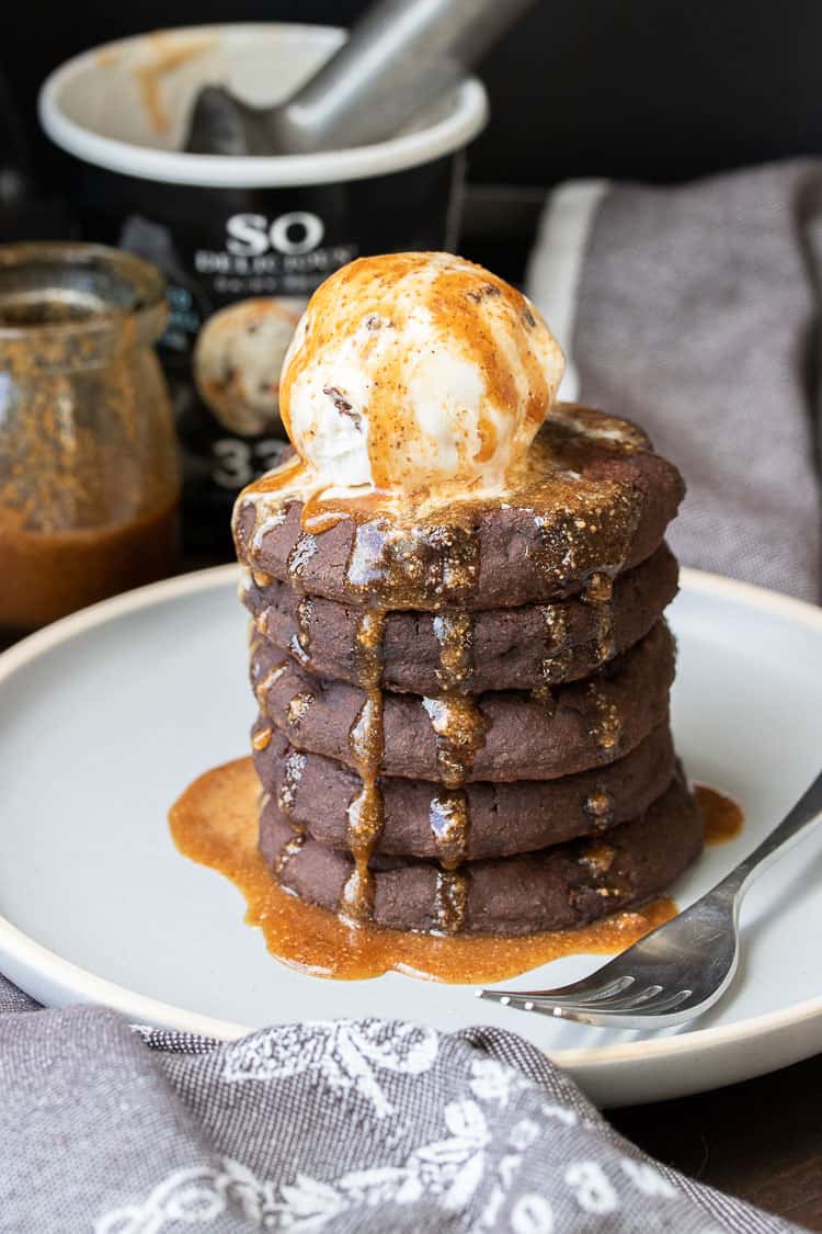 Gray plate with a pile of chocolate pancakes topped with a scoop of ice cream