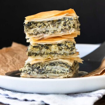 Pile of three pieces of spanakopita on a white plate