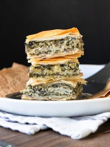 Pile of three pieces of spanakopita on a white plate