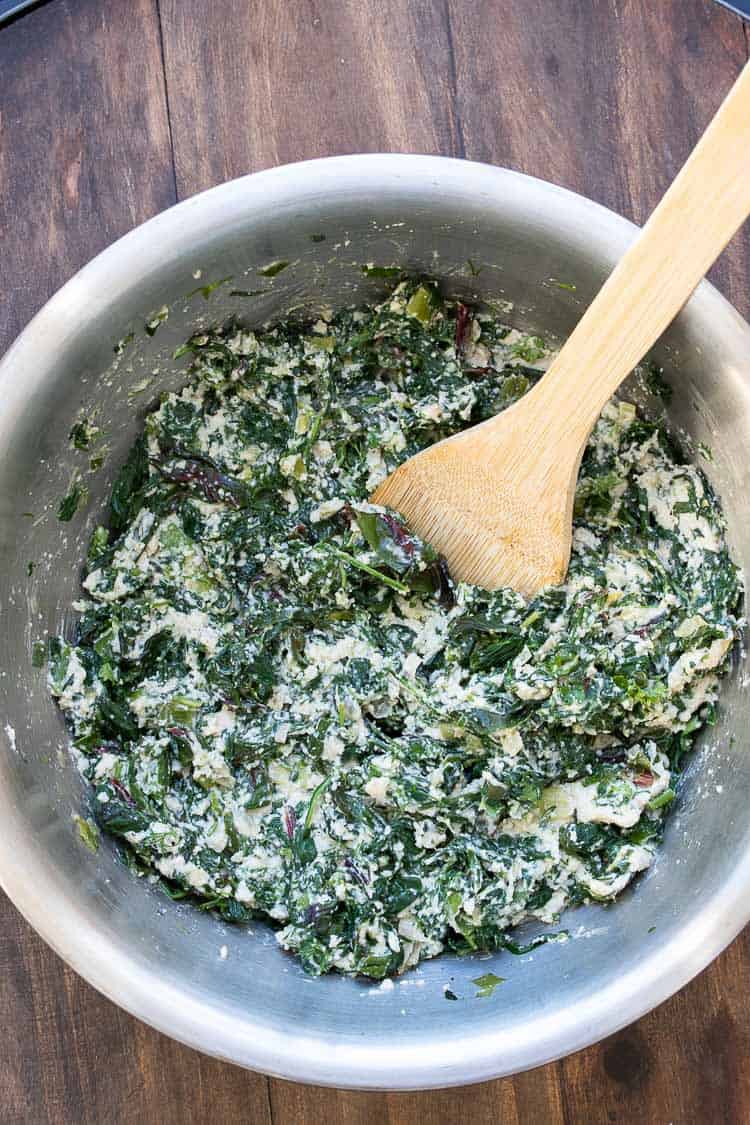 Filling of sautéed spinach and chopped creamy cashew mixture in a silver bowl