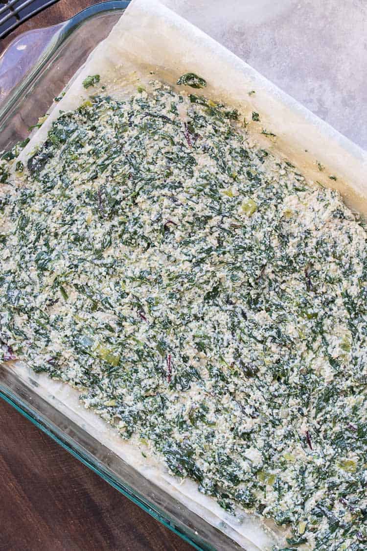 Spinach and chopped creamy cashew mixture spread over phyllo (filo) sheets layered in a glass baking dish