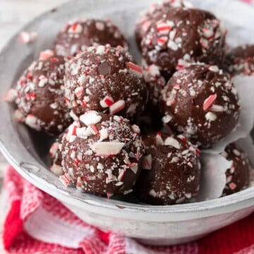 White bowl filled with chocolate peppermint candy cane balls on a red checkered towel