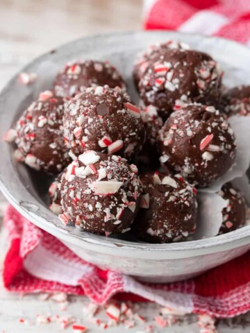 White bowl filled with chocolate peppermint candy cane balls on a red checkered towel