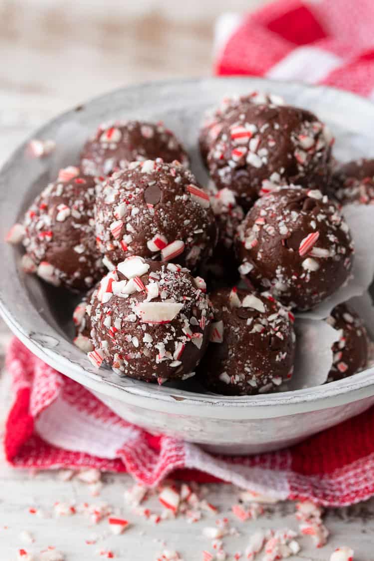 White bowl filled with chocolate peppermint candy cane balls on a red checkered towel