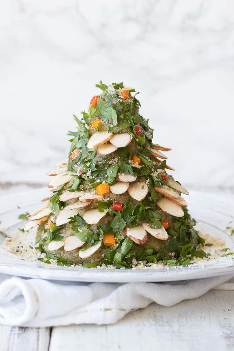 Cheese ball decorated like a Christmas tree with chopped herbs, veggies and slivered almonds