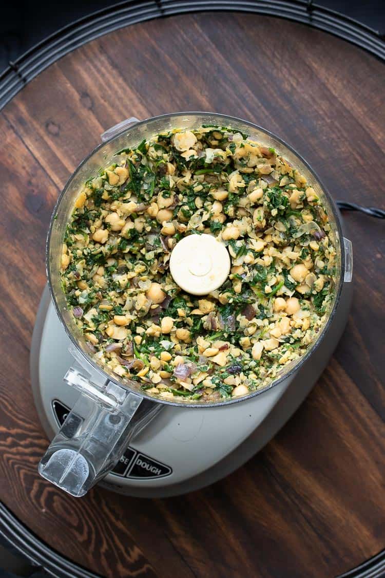 Top view of chickpeas and spinach being pulsed in a food processor