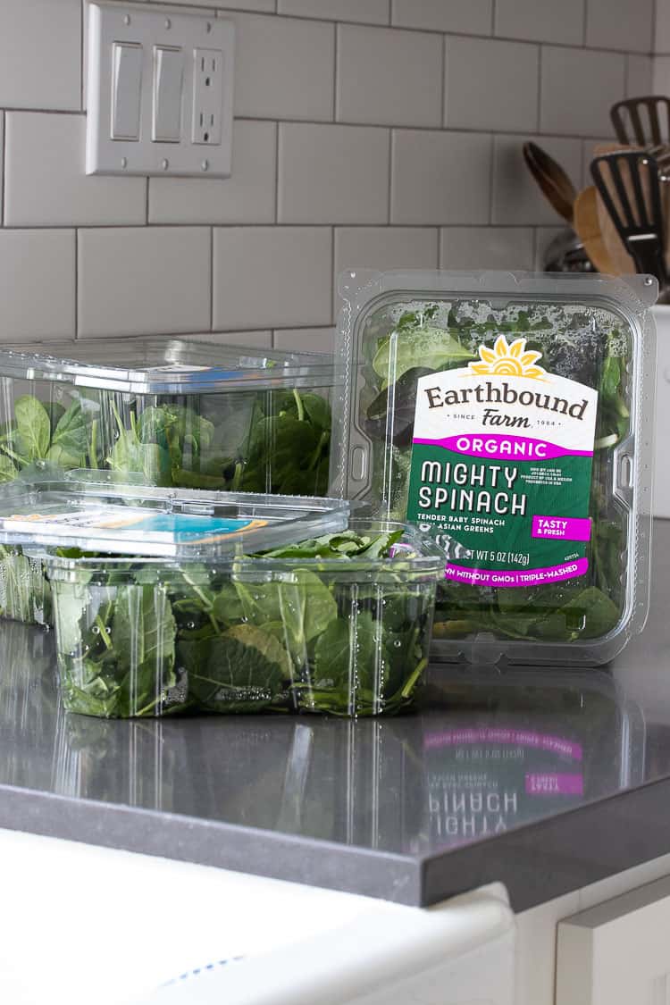 Plastic containers of Earthbound Farm Organic greens on kitchen counter