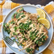 Two spinach and chickpea enchiladas on a grey plate with creamy drizzle on top