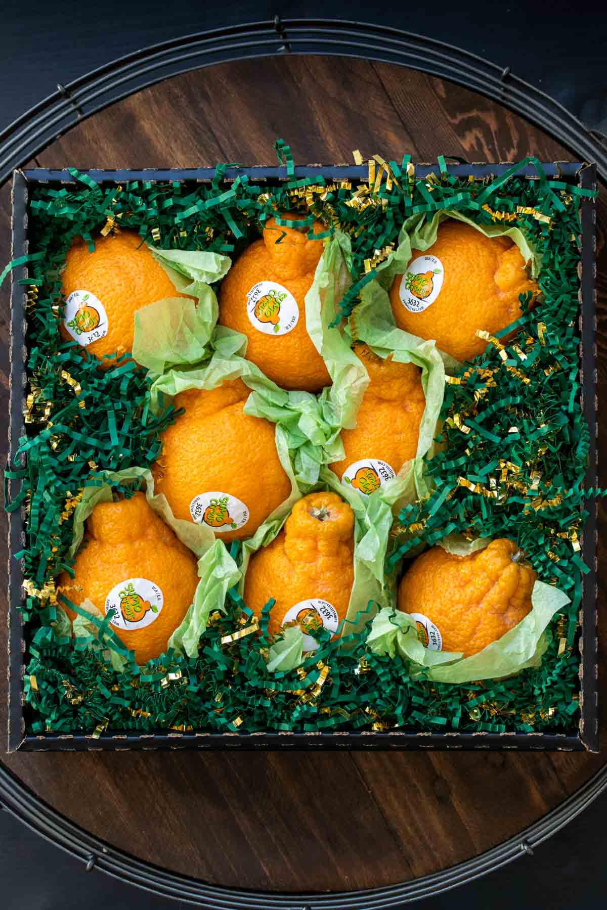 Oranges in box filled with green paper grass shreds