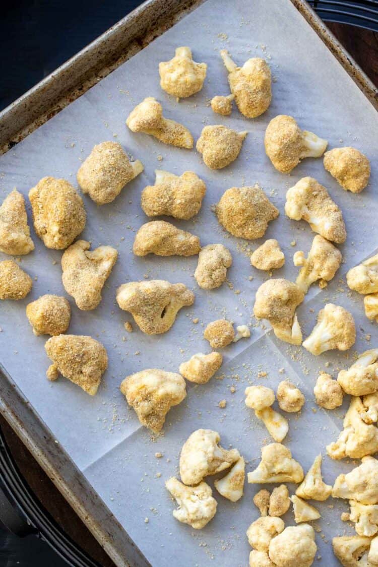 Cookie sheet with cauliflower pieces coated with breading