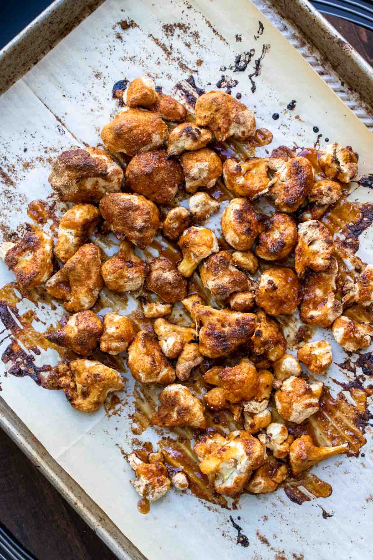 Crispy baked cauliflower covered in brown orange sauce on a cookie sheet