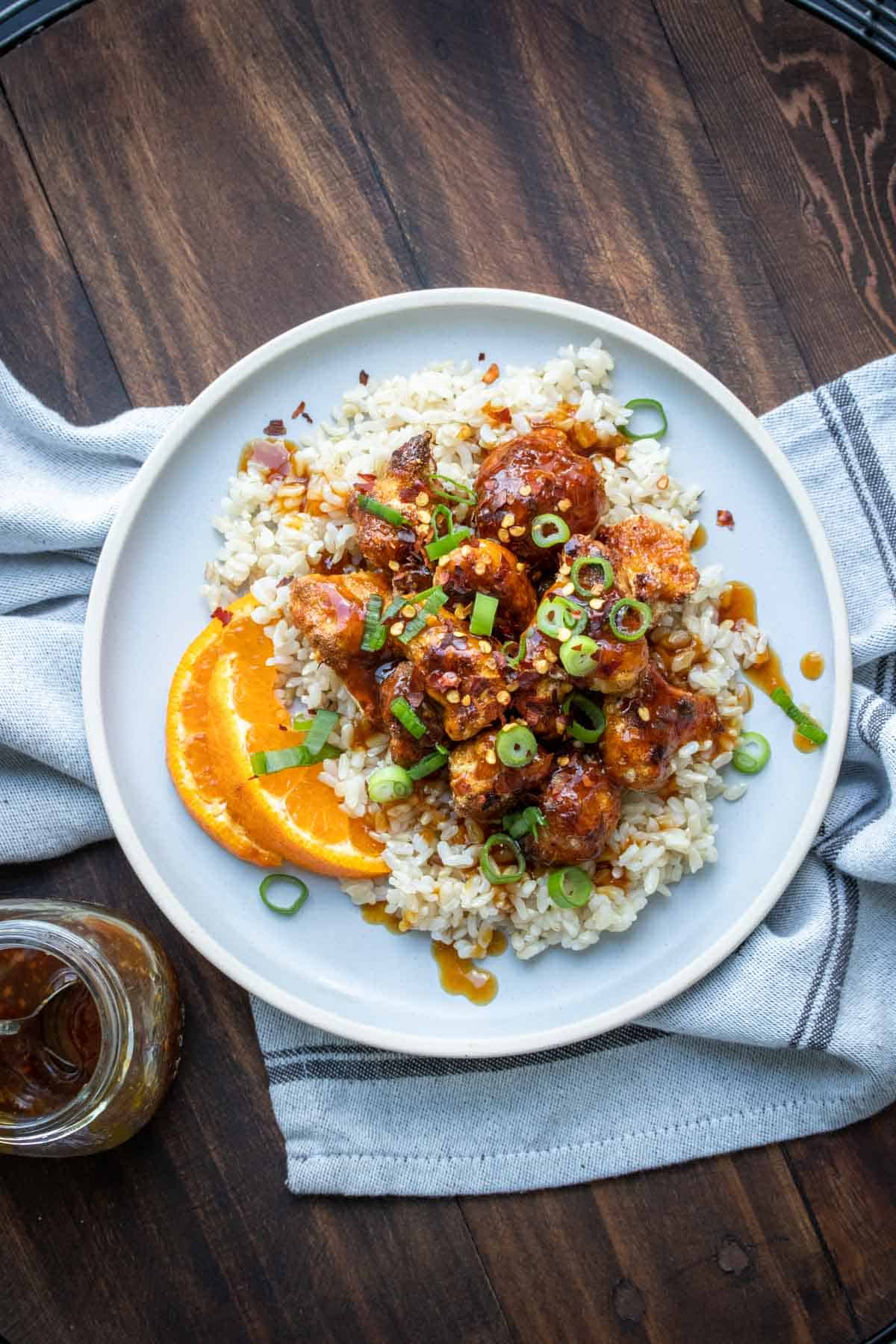 Grey plate with rice and crispy browned cauliflower covered in orange sauce