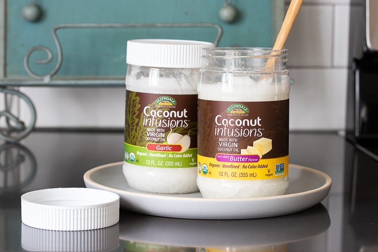 Two jars of coconut oil on a white plate on the kitchen counter