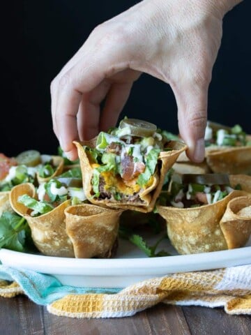 Hand picking up a half eaten crunchy taco cup with filling showing